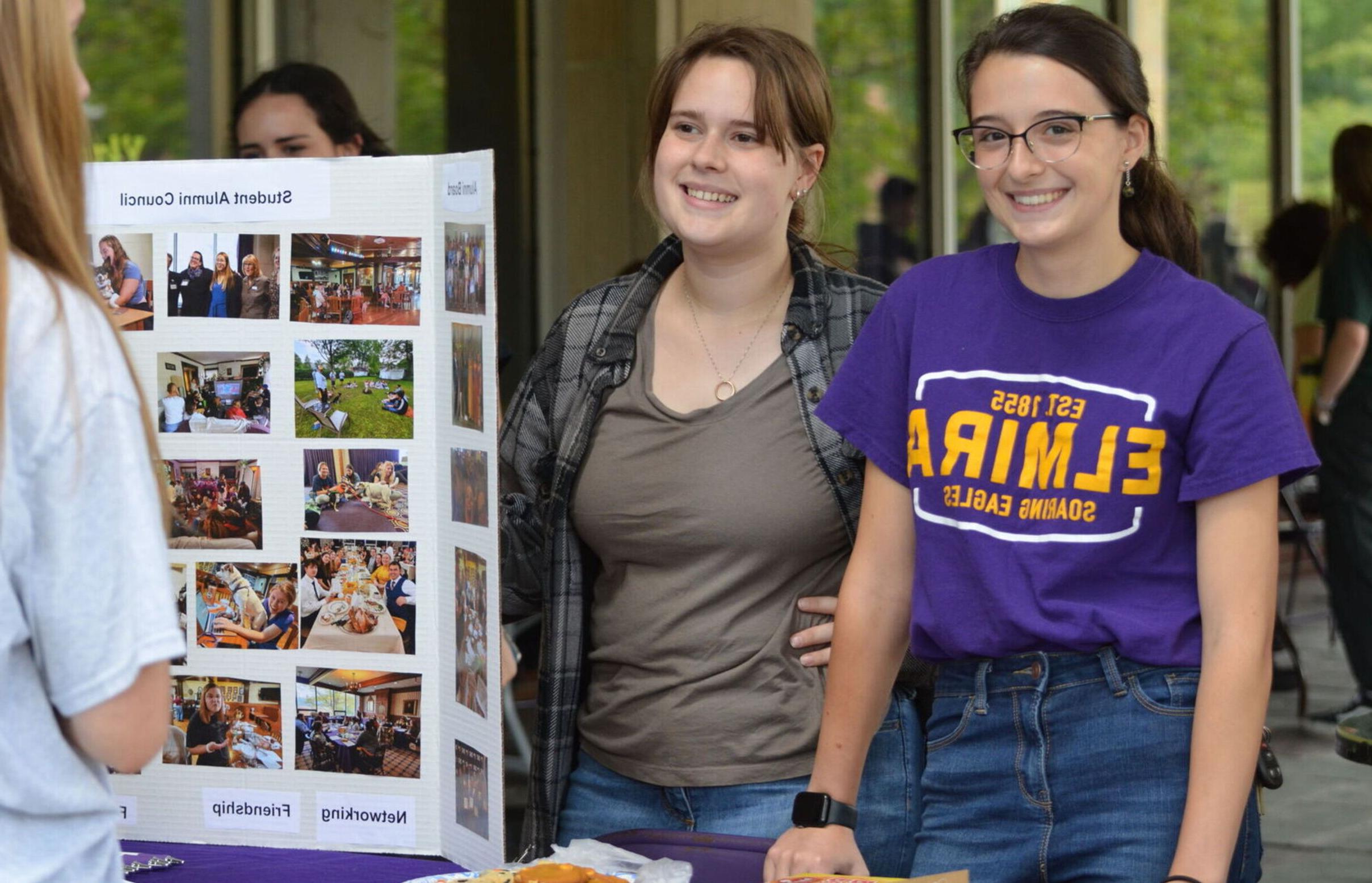 Two female students greet guests at the Student Alumni Council table