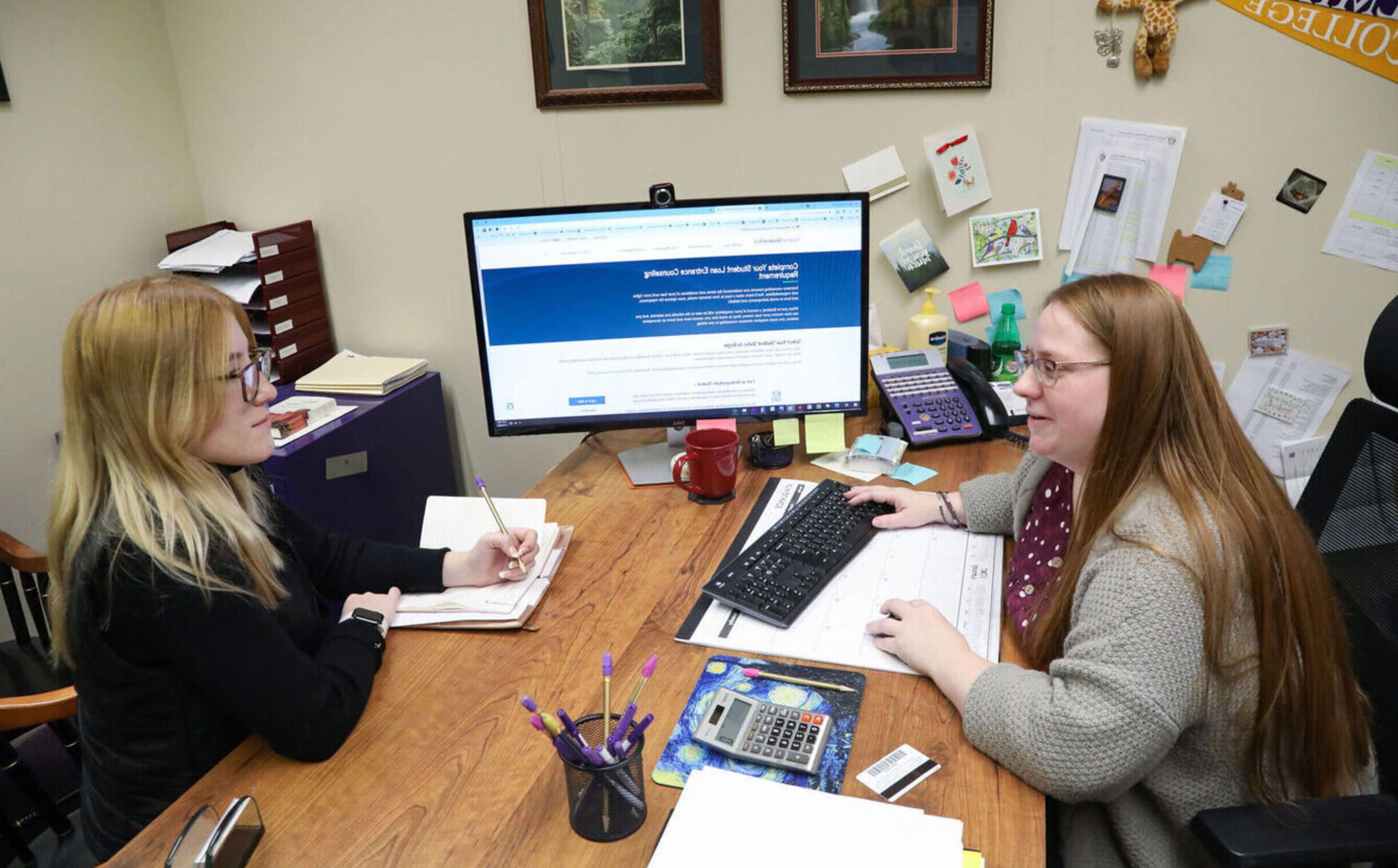 A financial aid worker meets with a student in her office