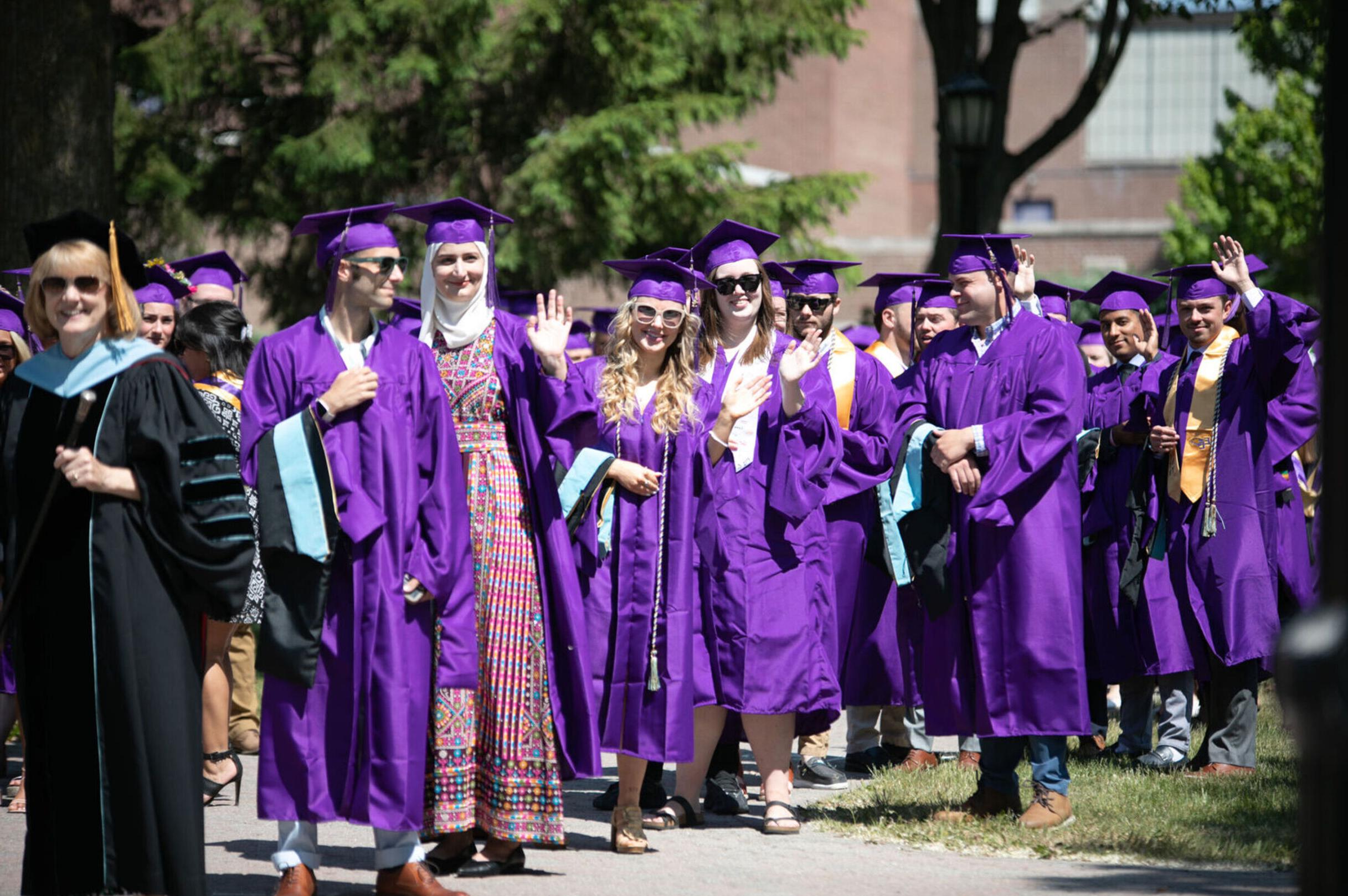 A group of Class of 2023 graduates wave at the camera during Commencement