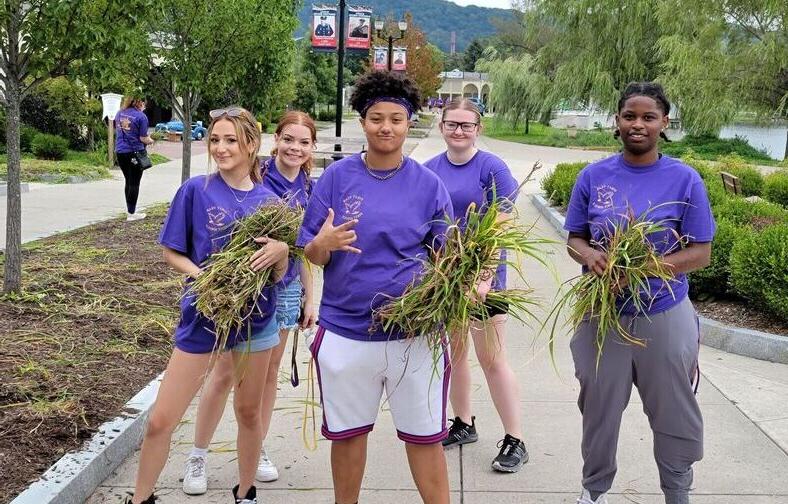 Students pose with weeds they pulled as part of their community service at Eldridge Park.