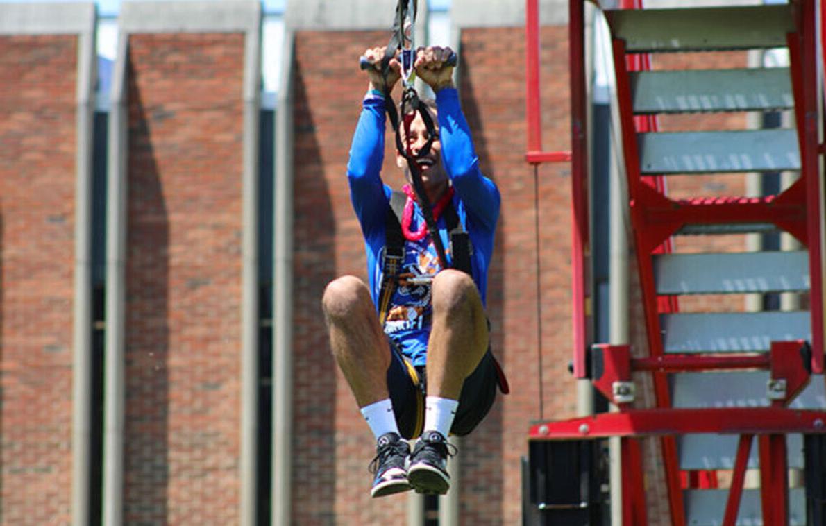 A male student rides the zip line at May Days