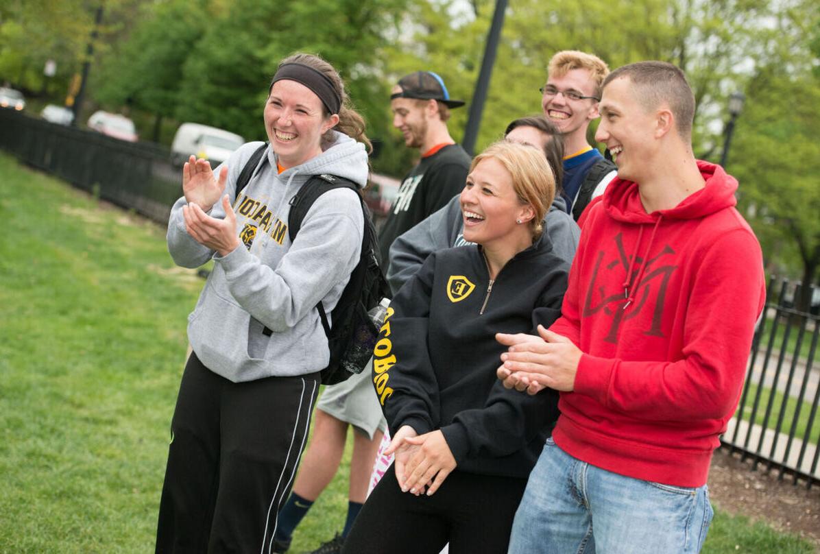 A group of students laugh while outside on the Elmira College campus